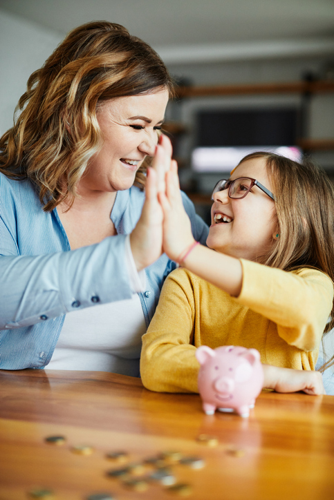 Mom and daughter high five with piggy bank