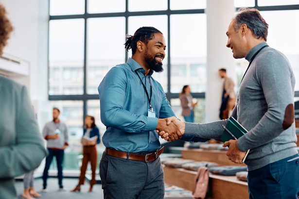 Team members shaking hands and smiling in communal work space